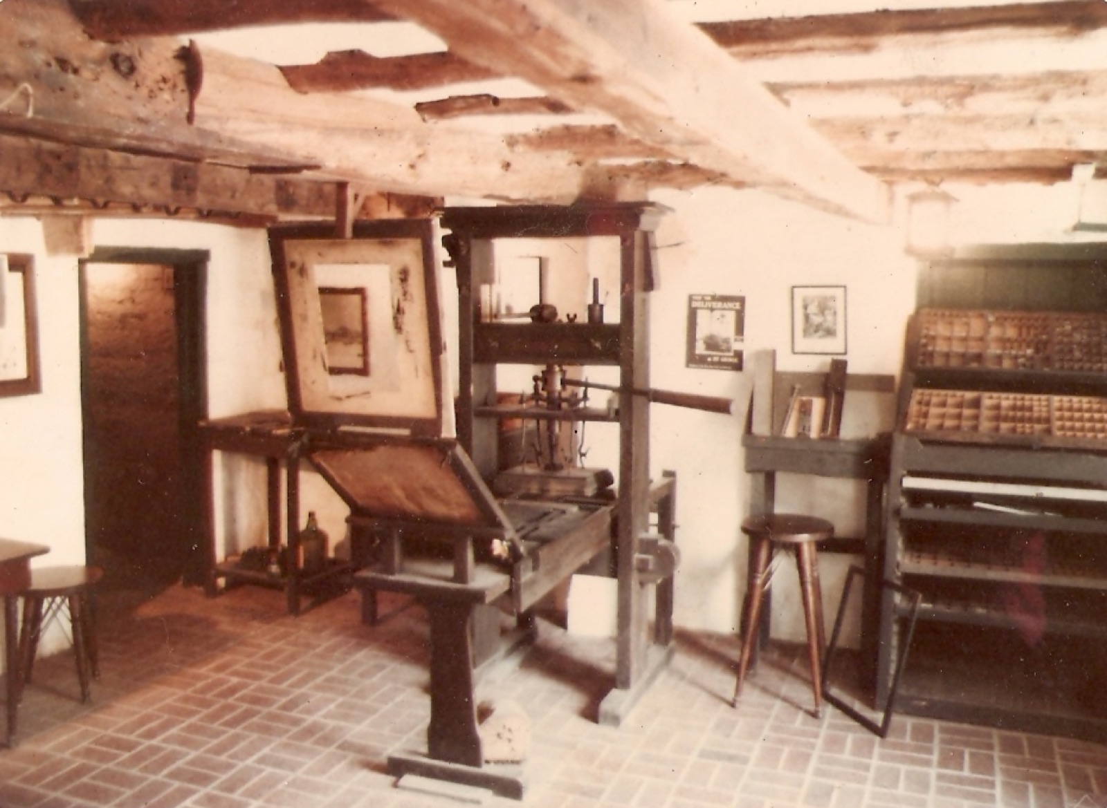 Un atelier de typographie traditionnel avec une presse à bras en bois, des casses de caractères en plomb et des composteurs.