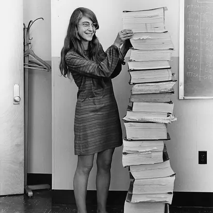 Margaret Hamilton en 1969, debout à côté d'une pile de listings du logiciel de vol Apollo aussi haute qu'elle