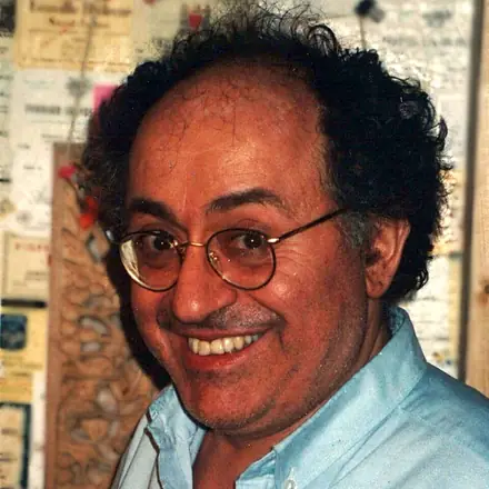 Photographie de Roland Moreno souriant, lunettes rondes et cheveux bouclés, en 1996